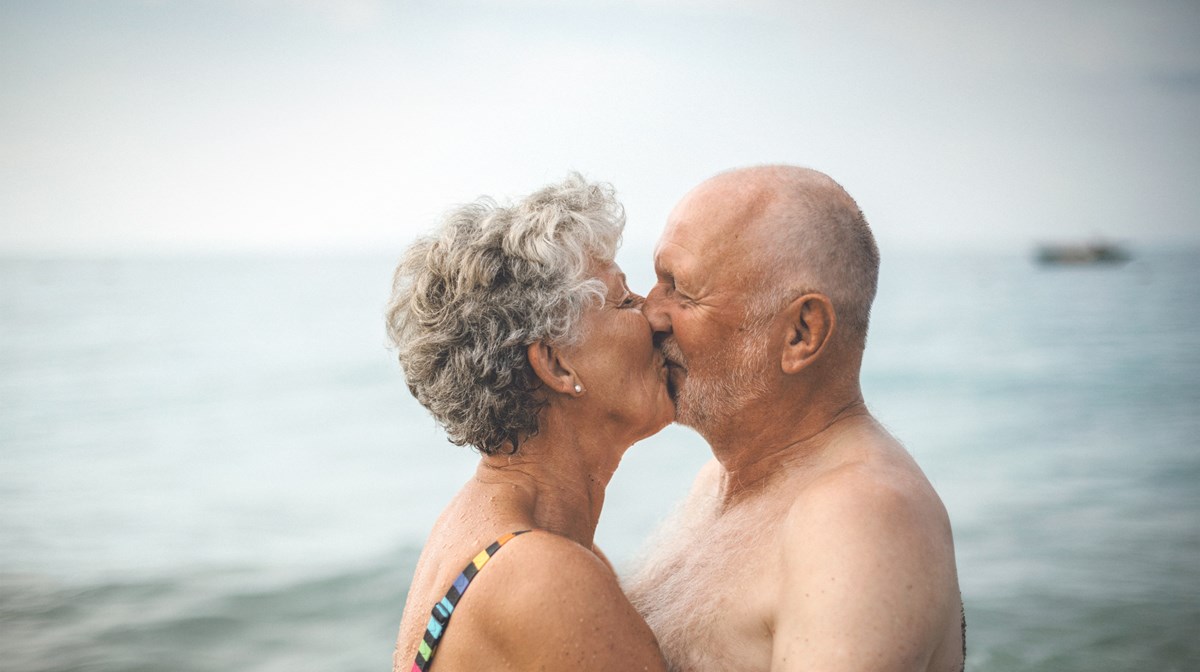 Ett äldre par kysser varandra ståendes i vattnet