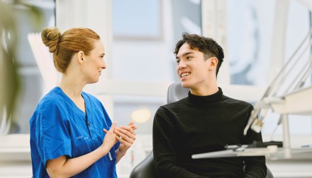 Kvinnlig tandhygienist på Folktandvården berättar om allt som ingår i Frisktandvård för en yngre manlig frisktandvårdspatient.