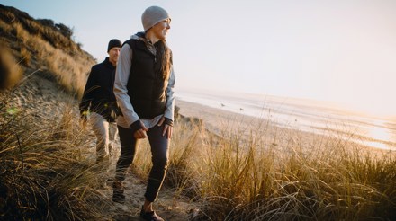 Två personer vandrar vid havet